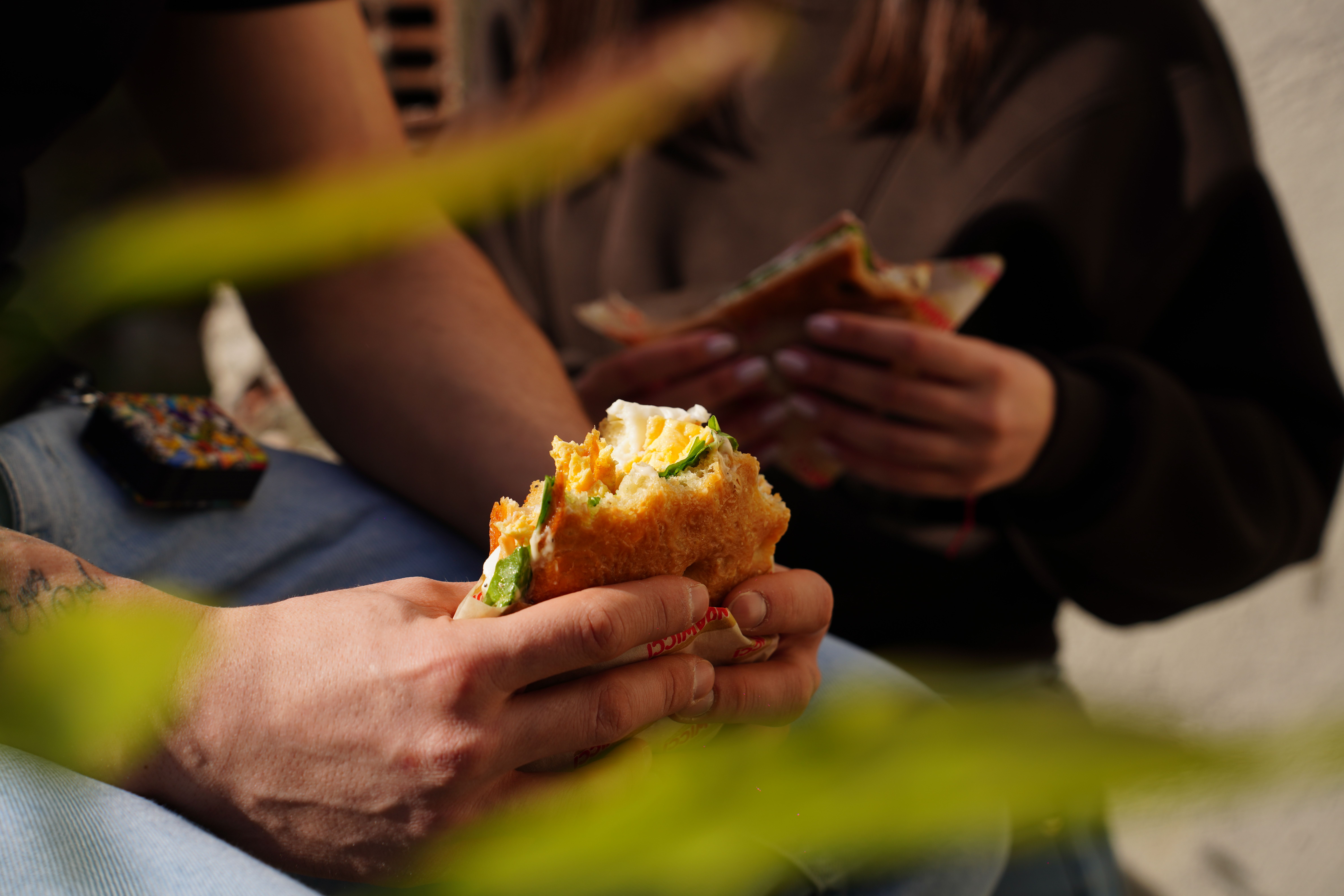 Hands holding a large wrapped kumru sandwich