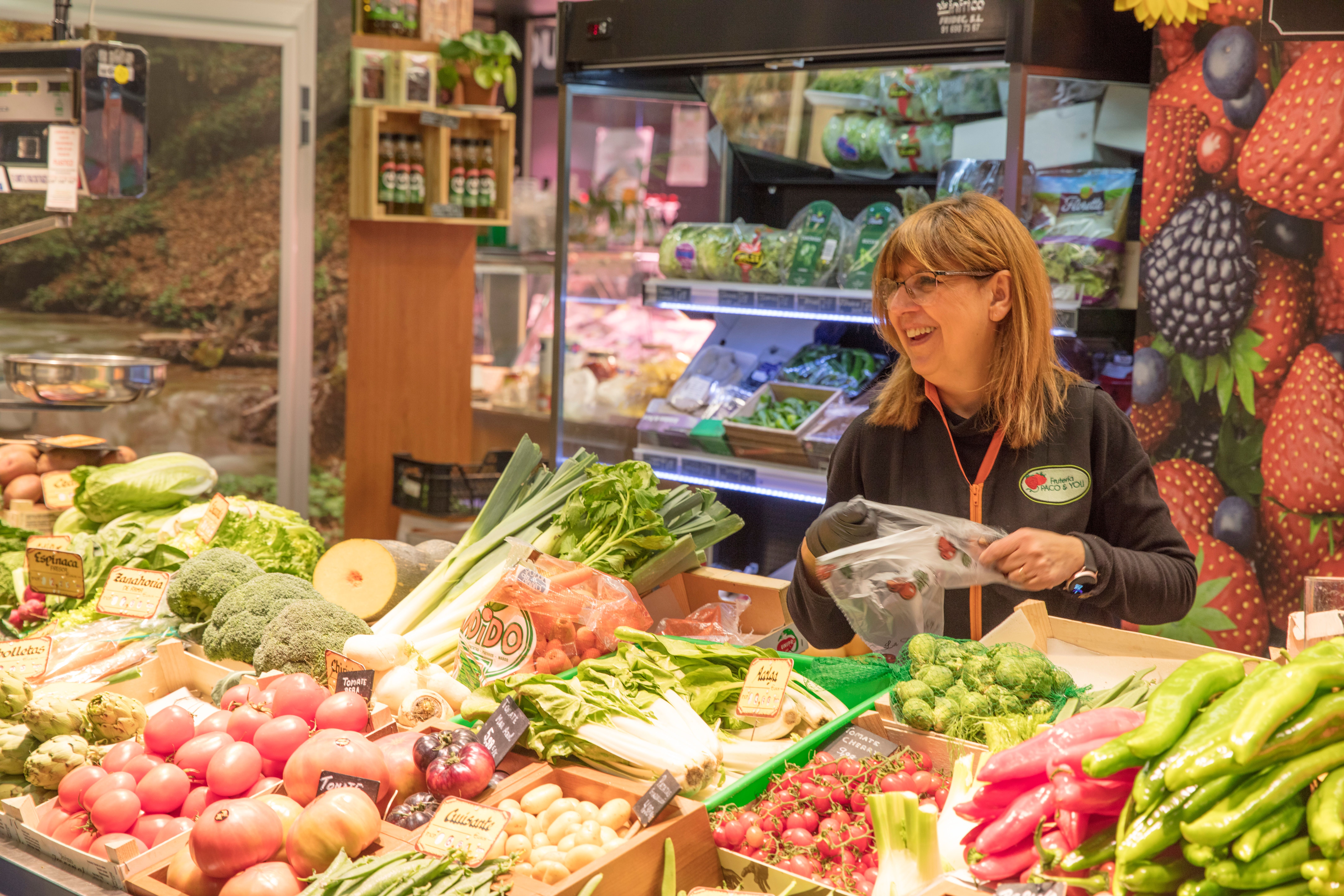 A customer smiling while holding a premium grocery bag in front of the store