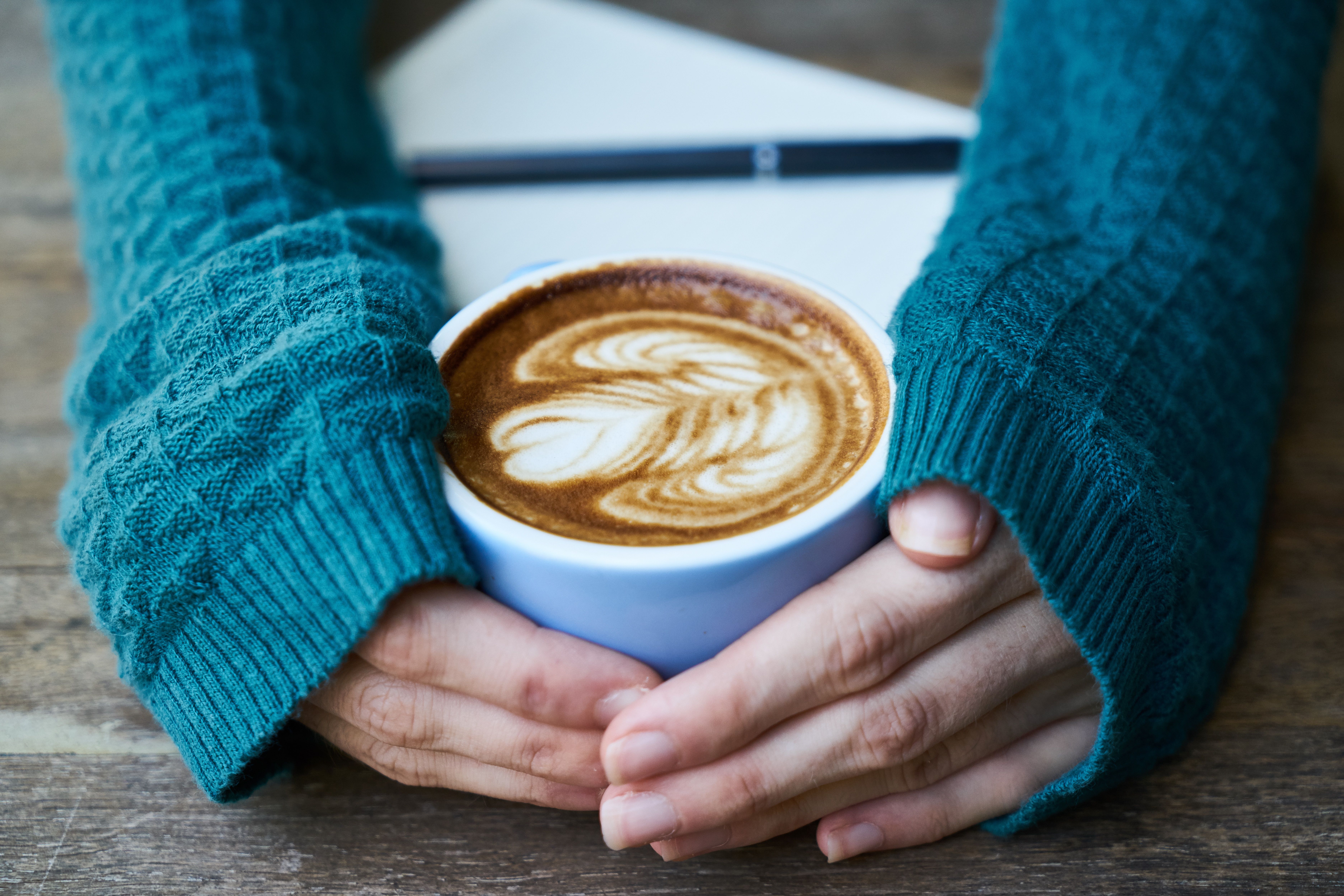 Hands holding a warm ceramic mug in a cozy setting