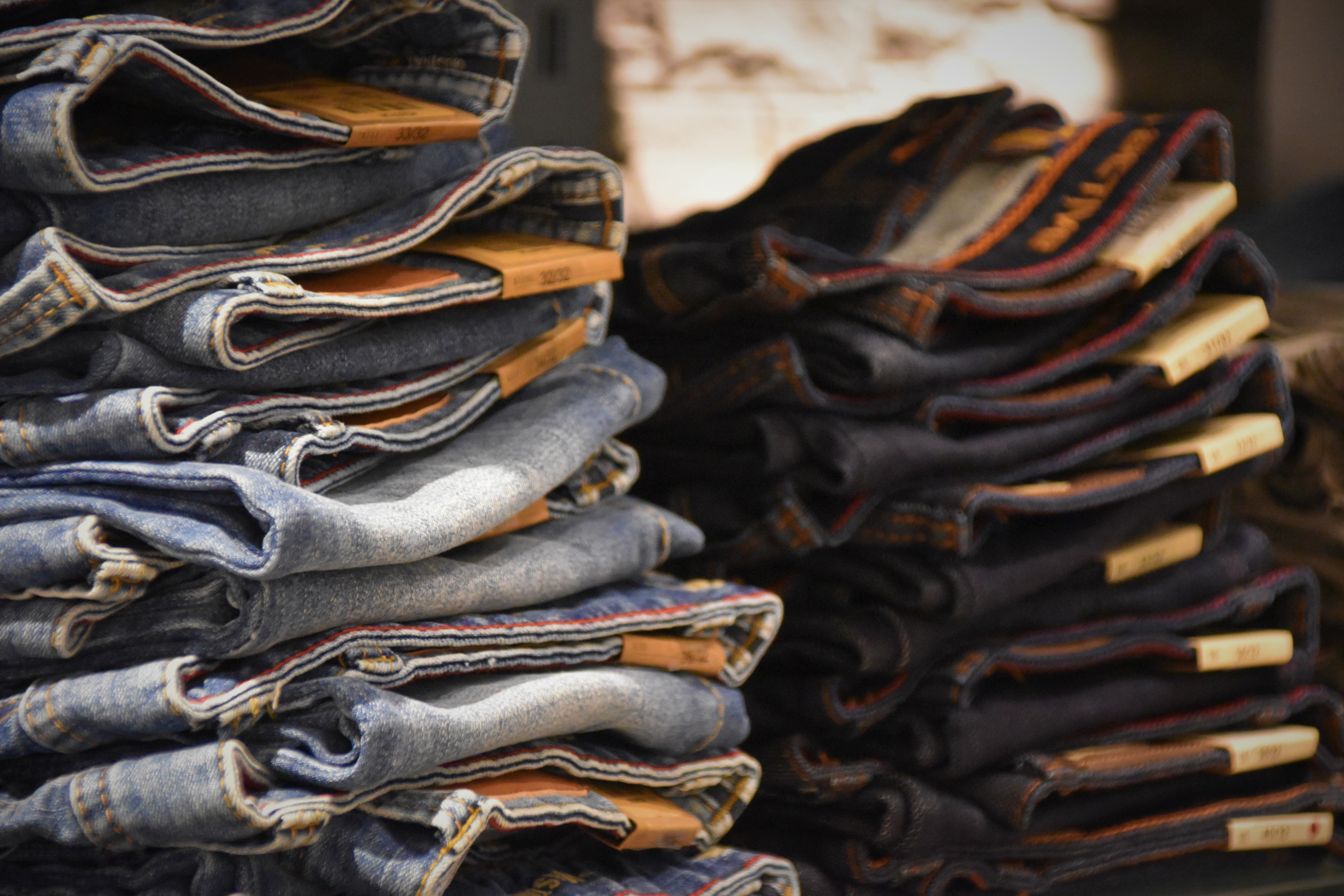Selection of curated denim jeans stacked on a wooden bench
