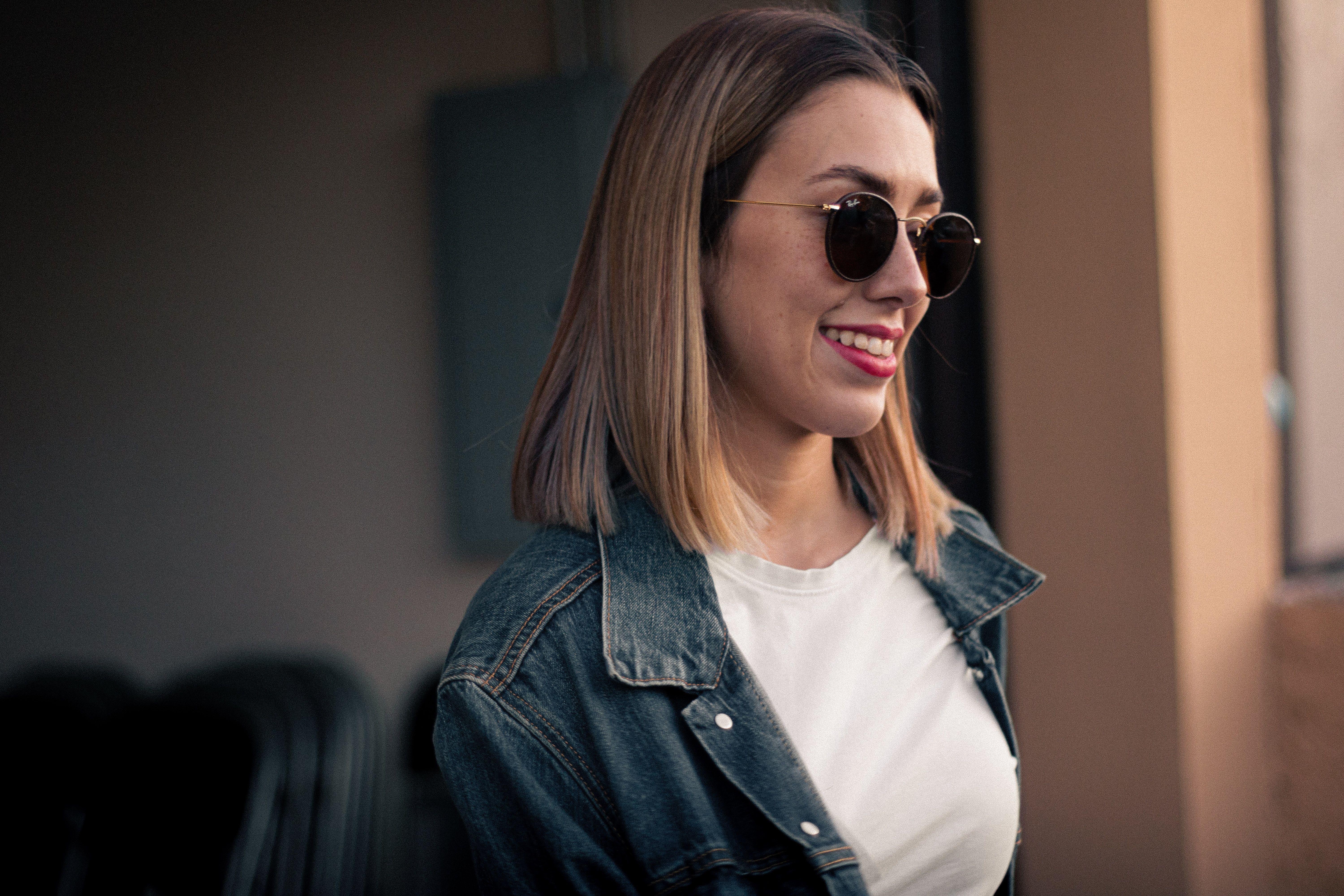 Young woman smiling while wearing a vintage denim jacket in a city street
