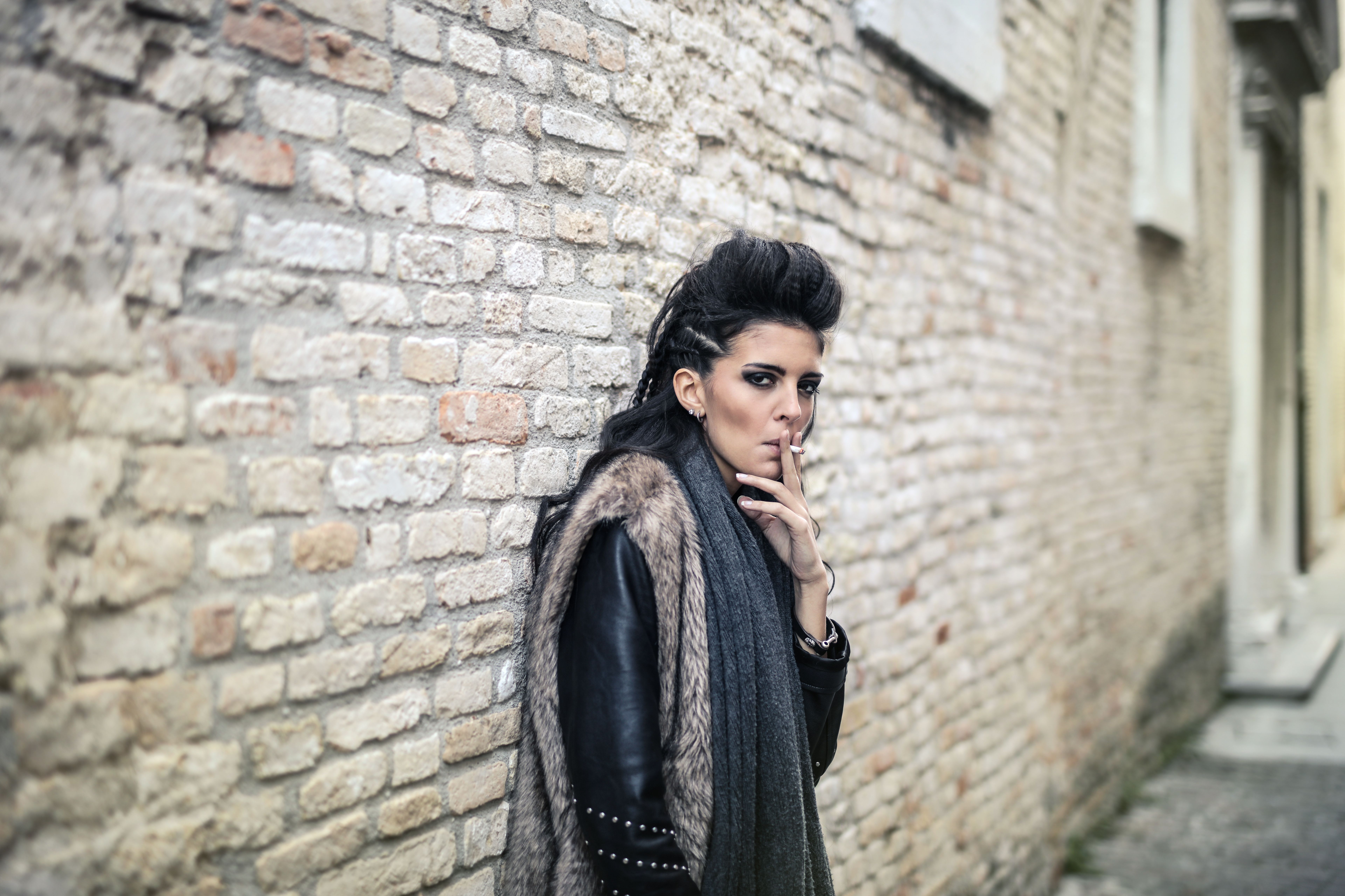 Woman posing with a vintage leather trench coat in a garden
