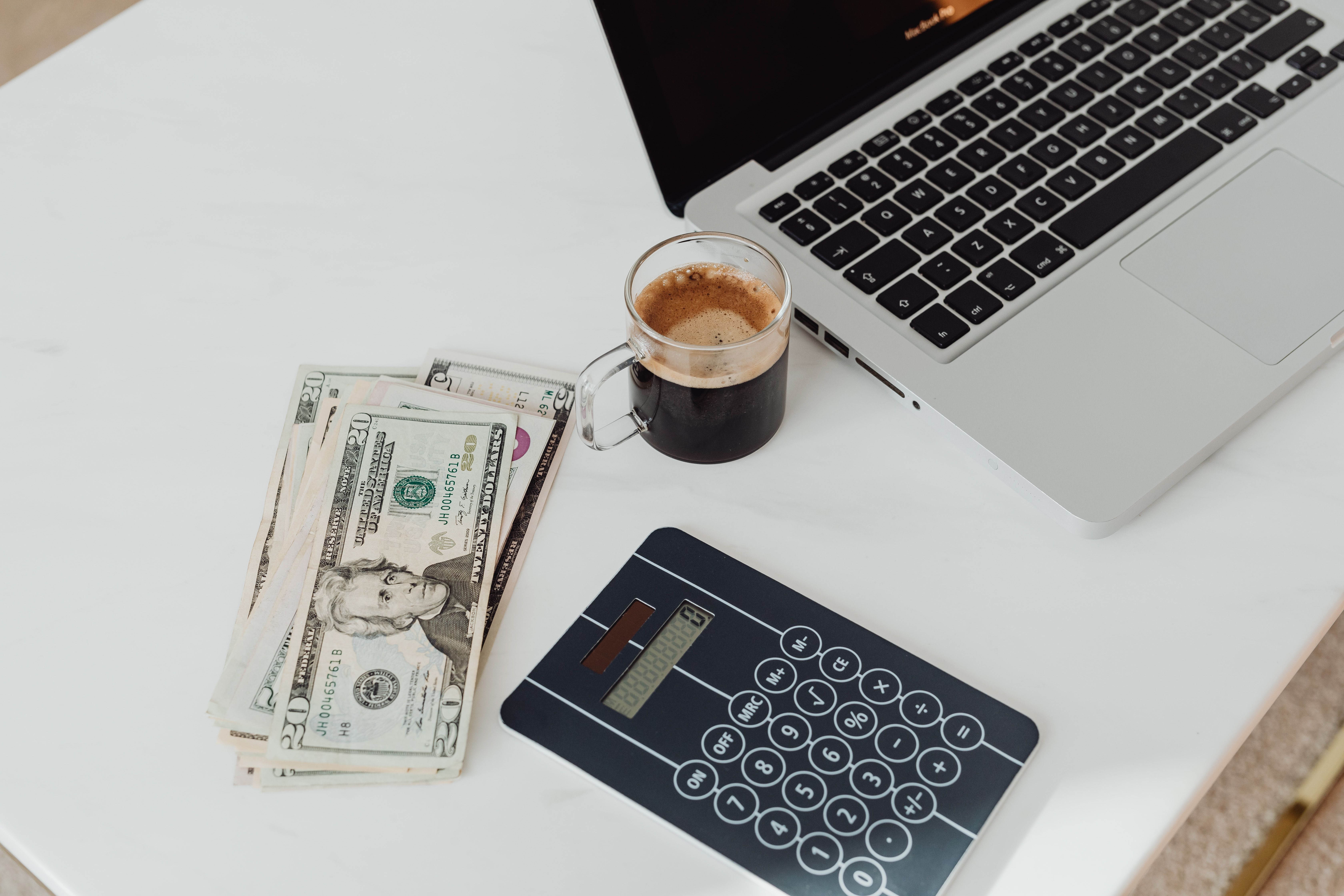 Cup of coffee next to a calculator on a desk