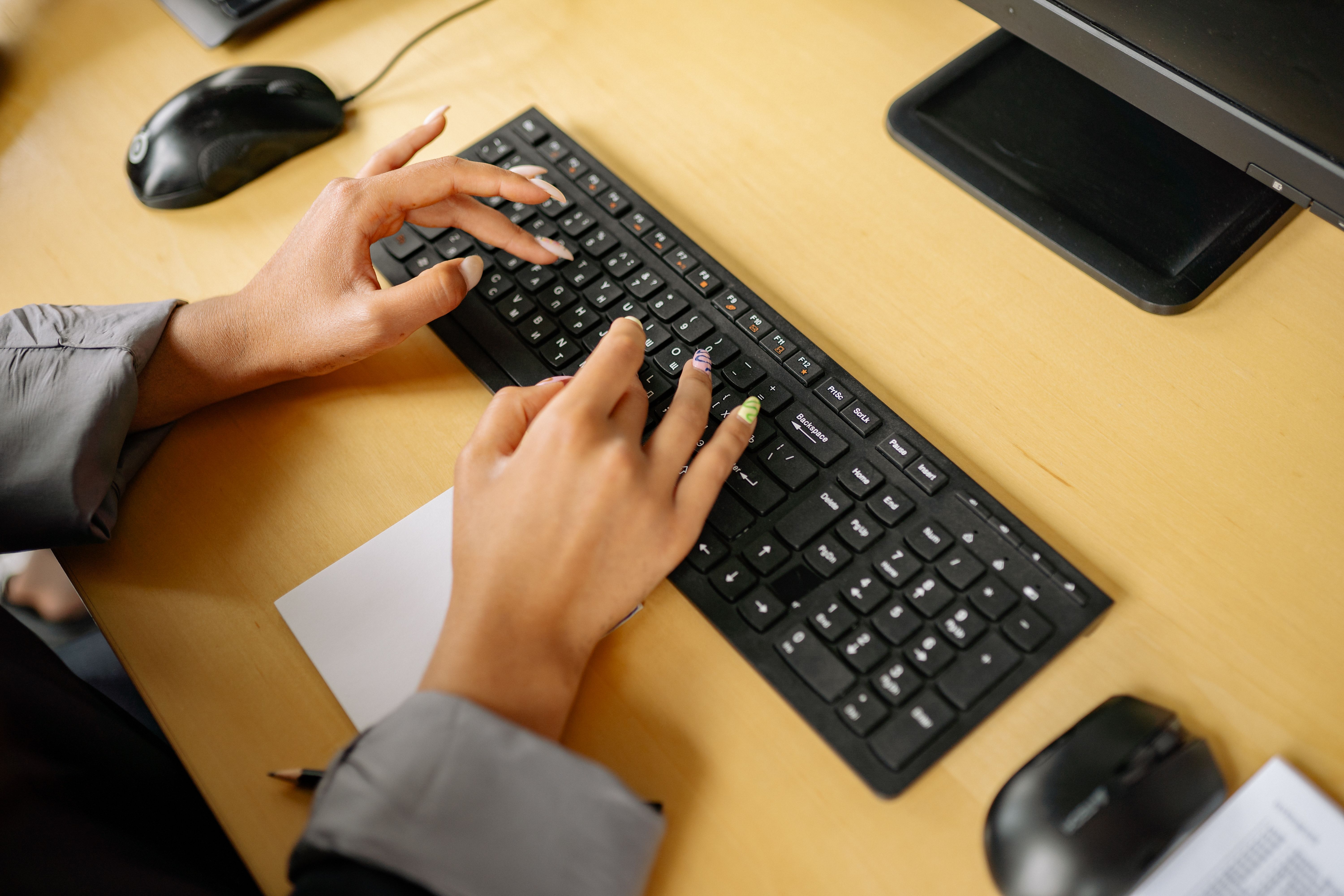 Person typing on a computer keyboard in a bright room