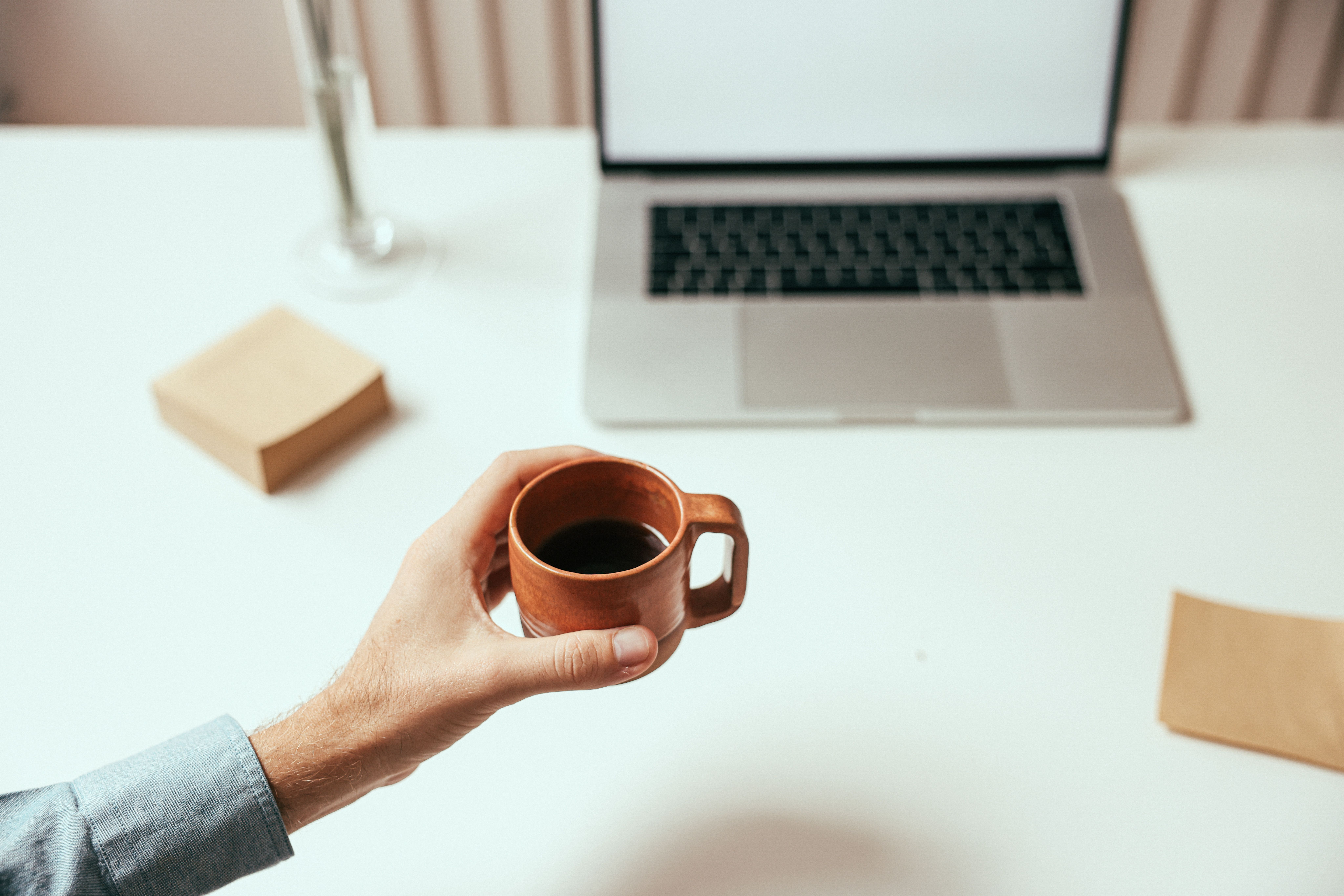 Coffee cup next to a laptop on a clean white desk