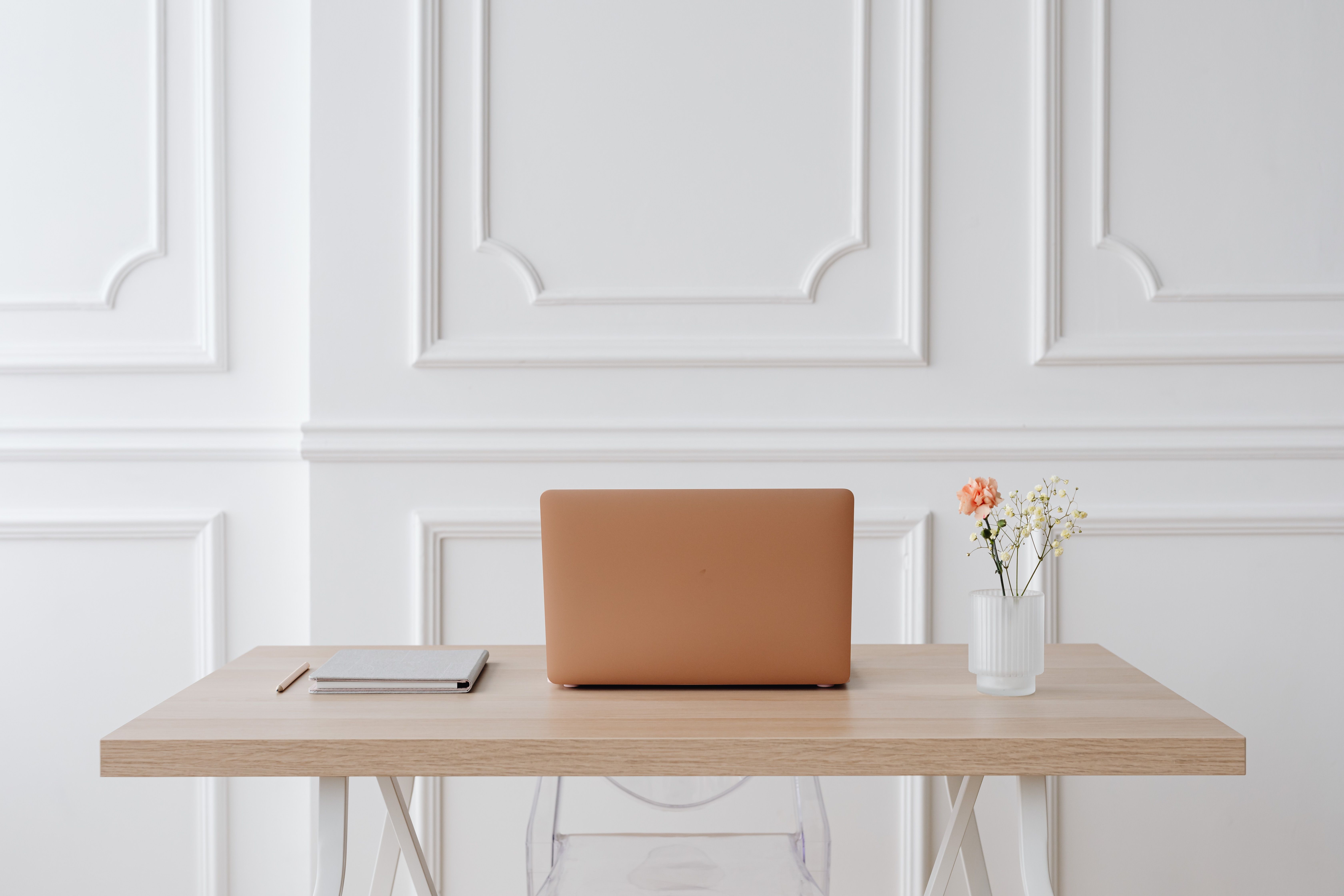 A clean, minimalist workspace with a laptop and a notebook