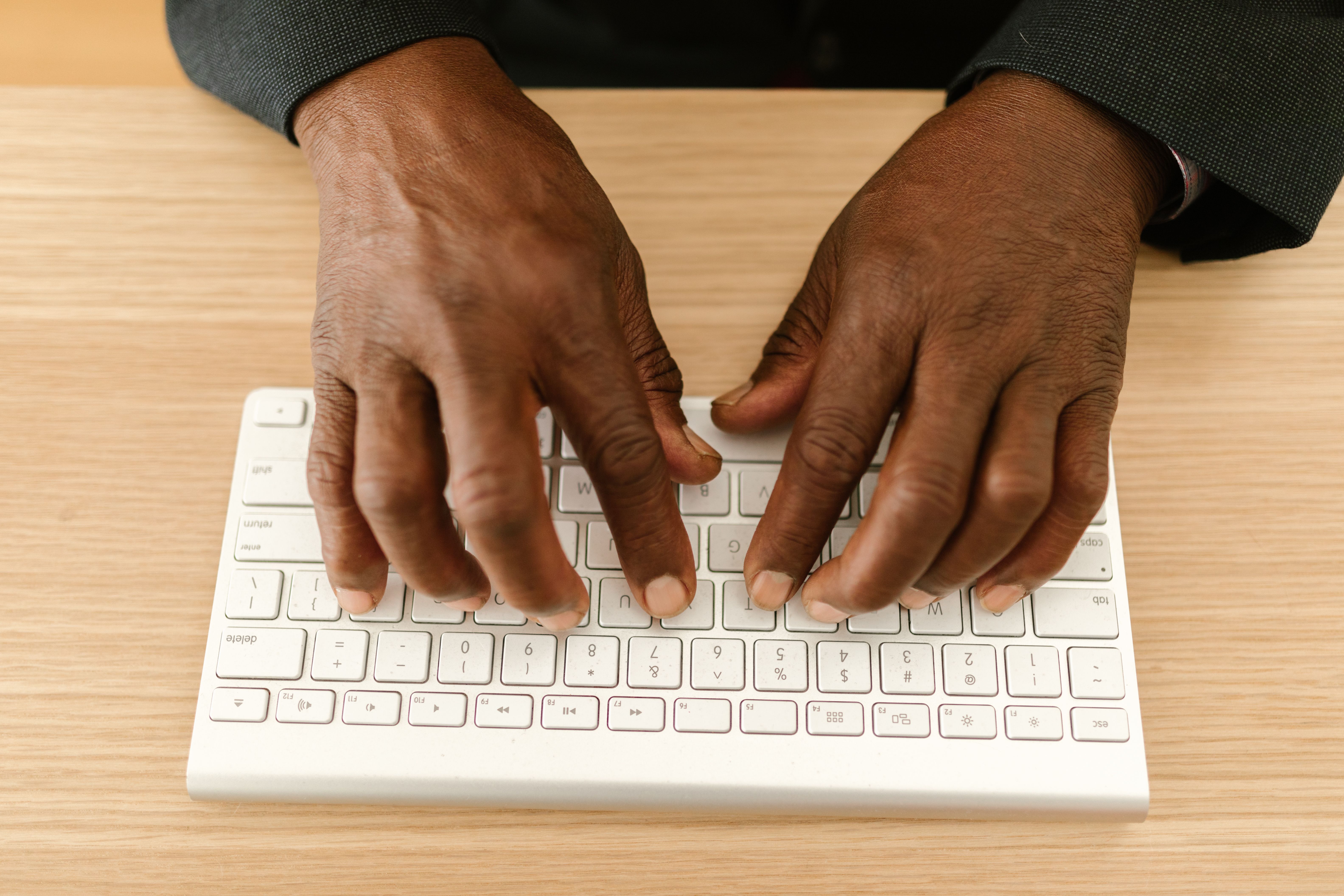 Close-up of a person typing on a laptop keyboard in a bright office
