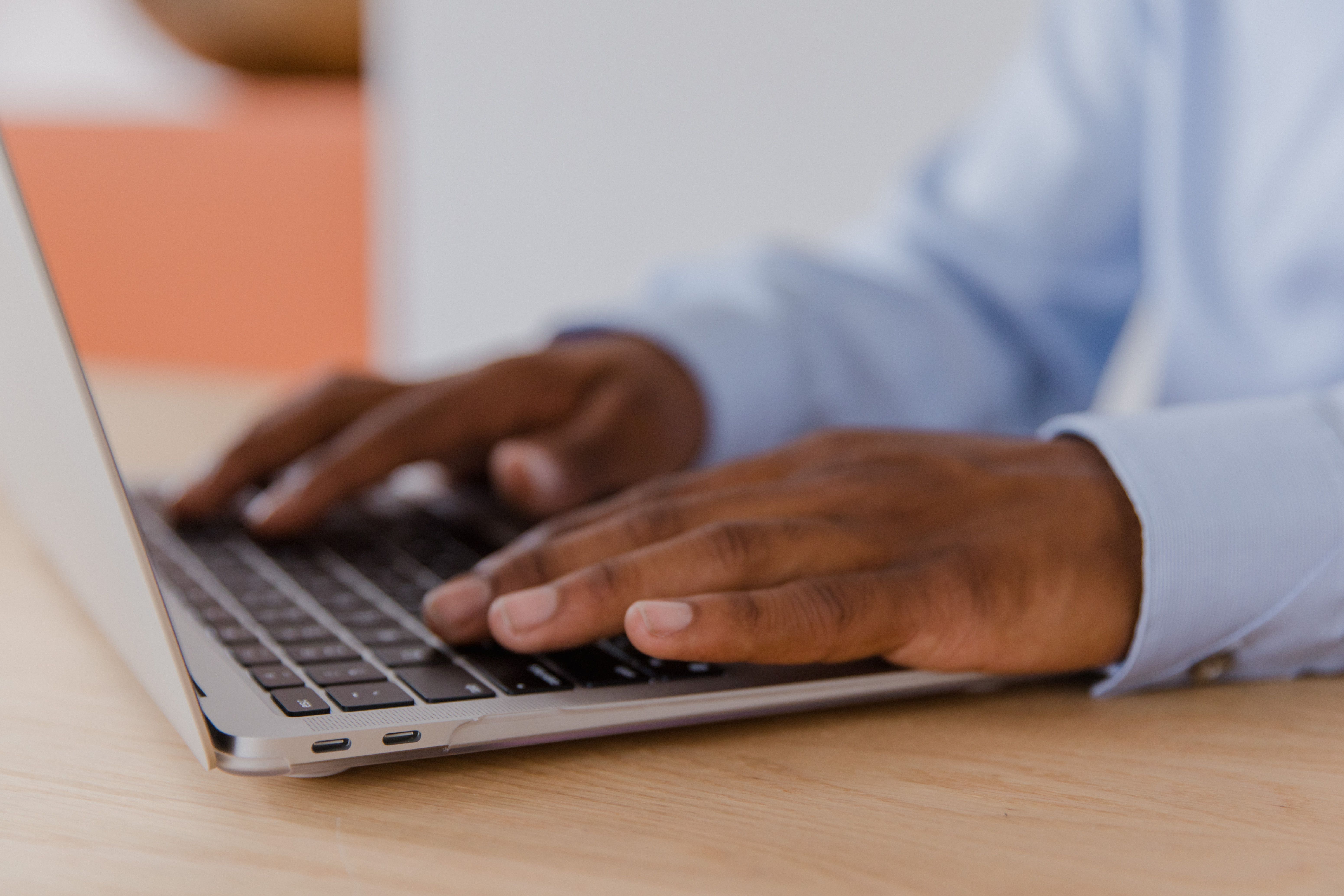 Close-up of hands typing on a laptop keyboard in a focused environment
