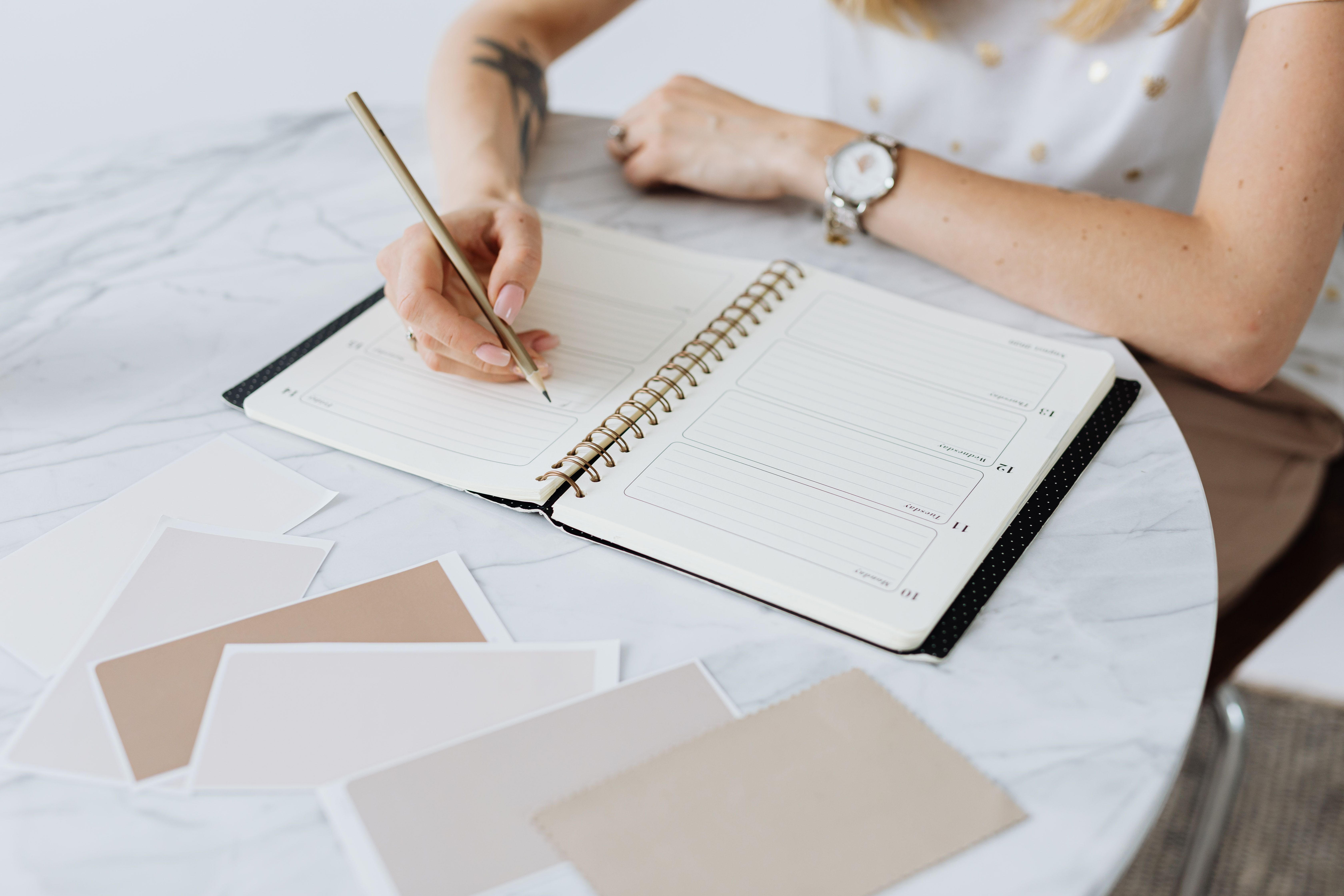 Person writing notes in a stylish leather-bound planner