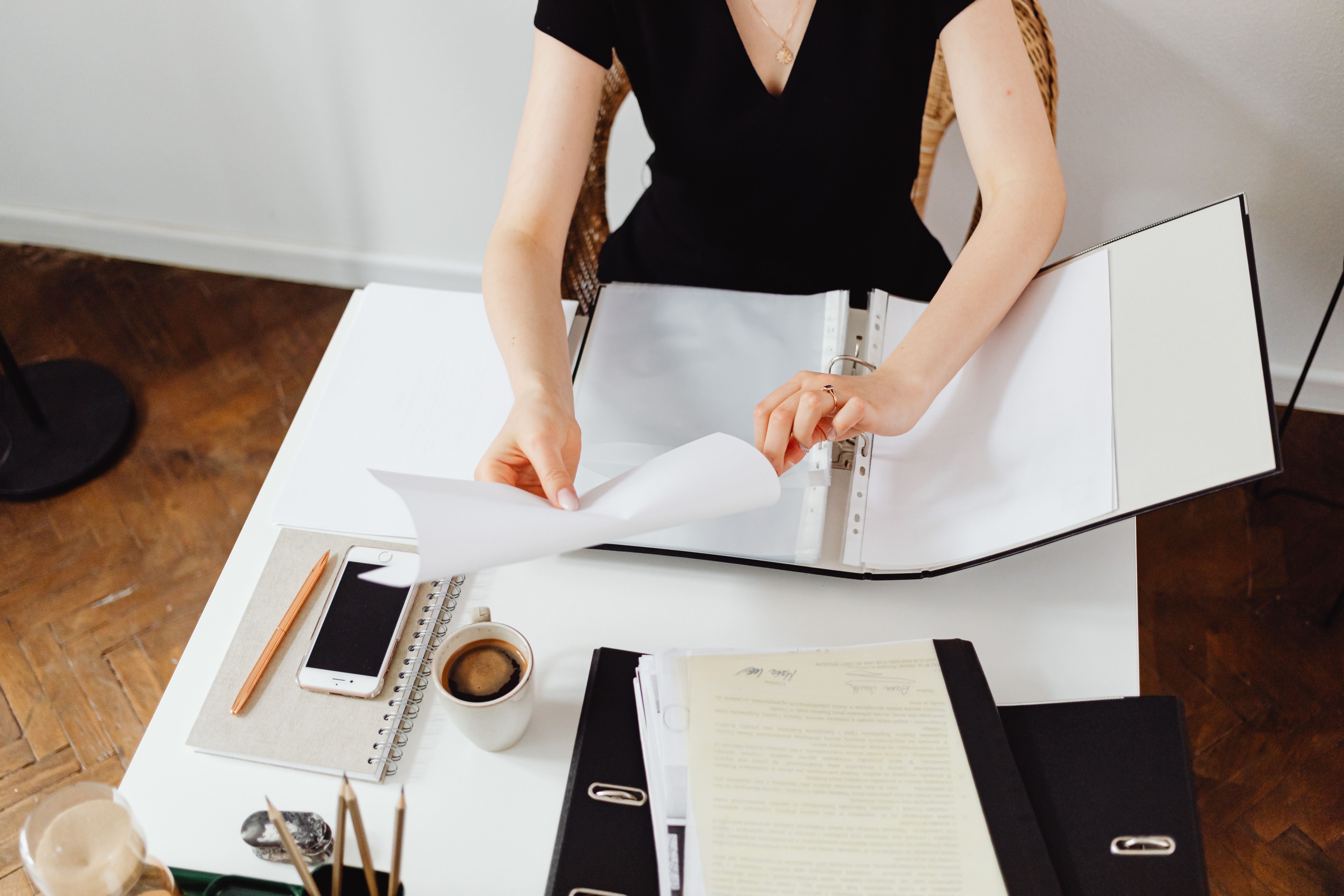 Hands filing documents into a binder with precision
