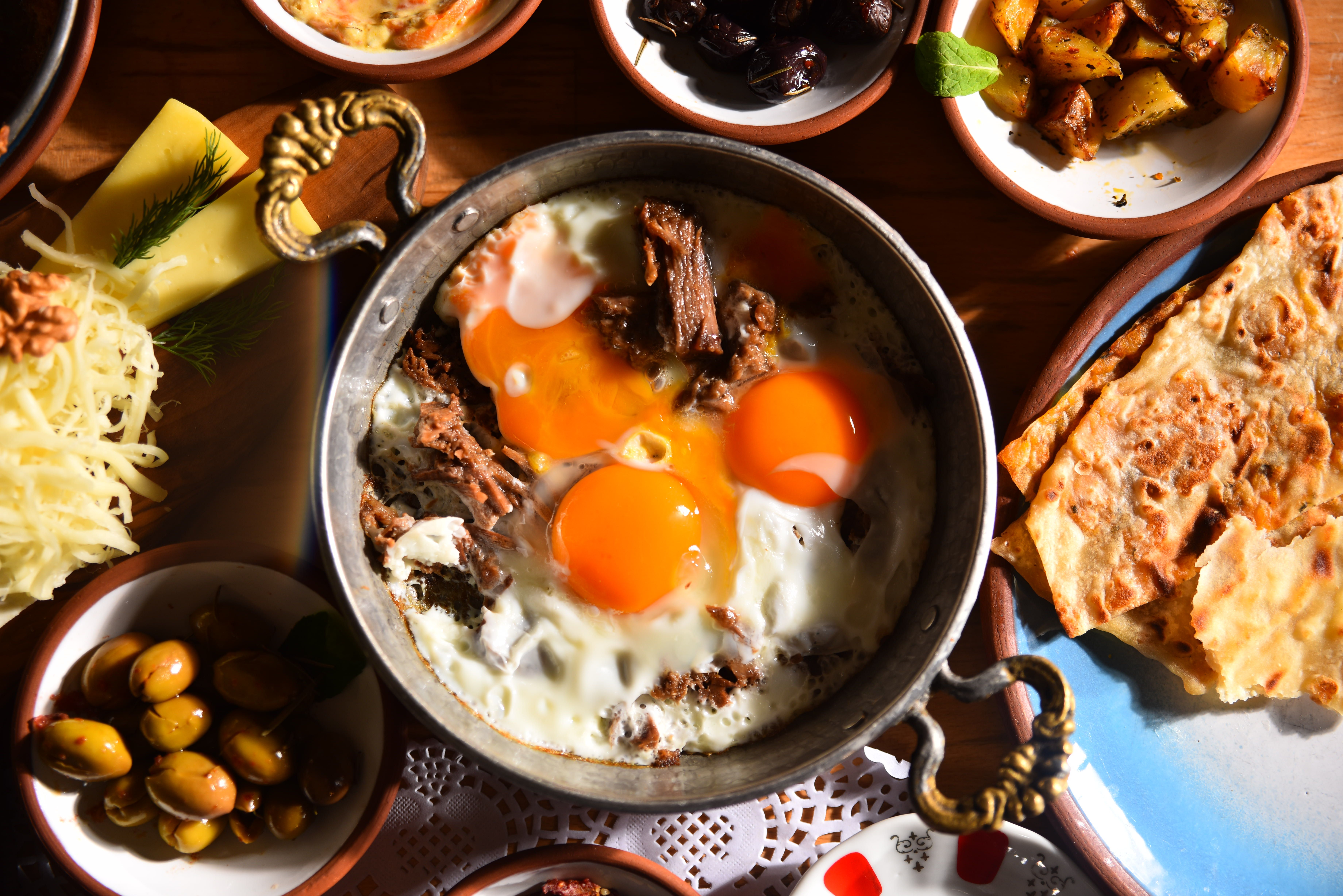 Traditional Turkish breakfast spread with olives, cheeses, and honey on a wooden table