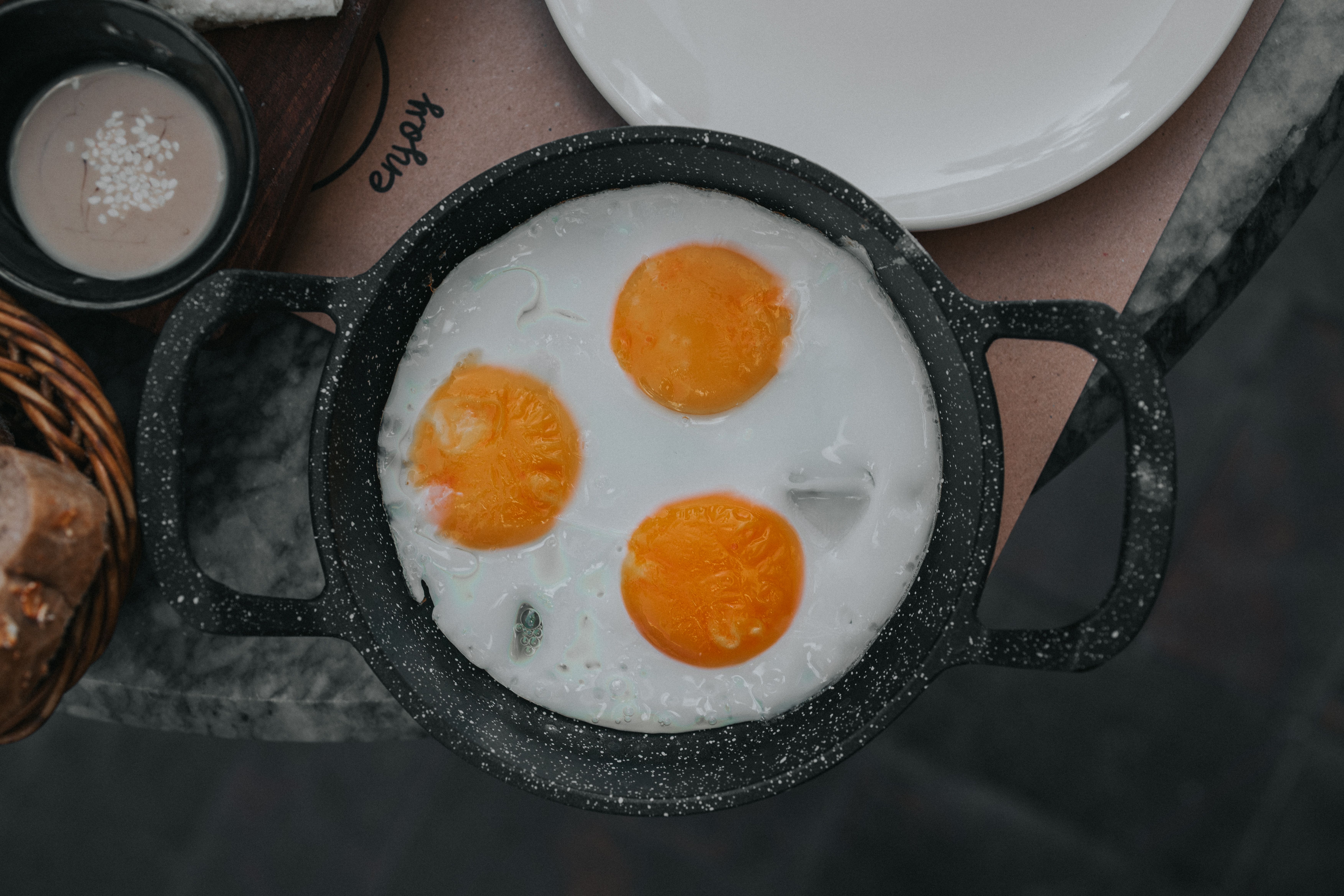 Two fried eggs in a small metal pan with butter