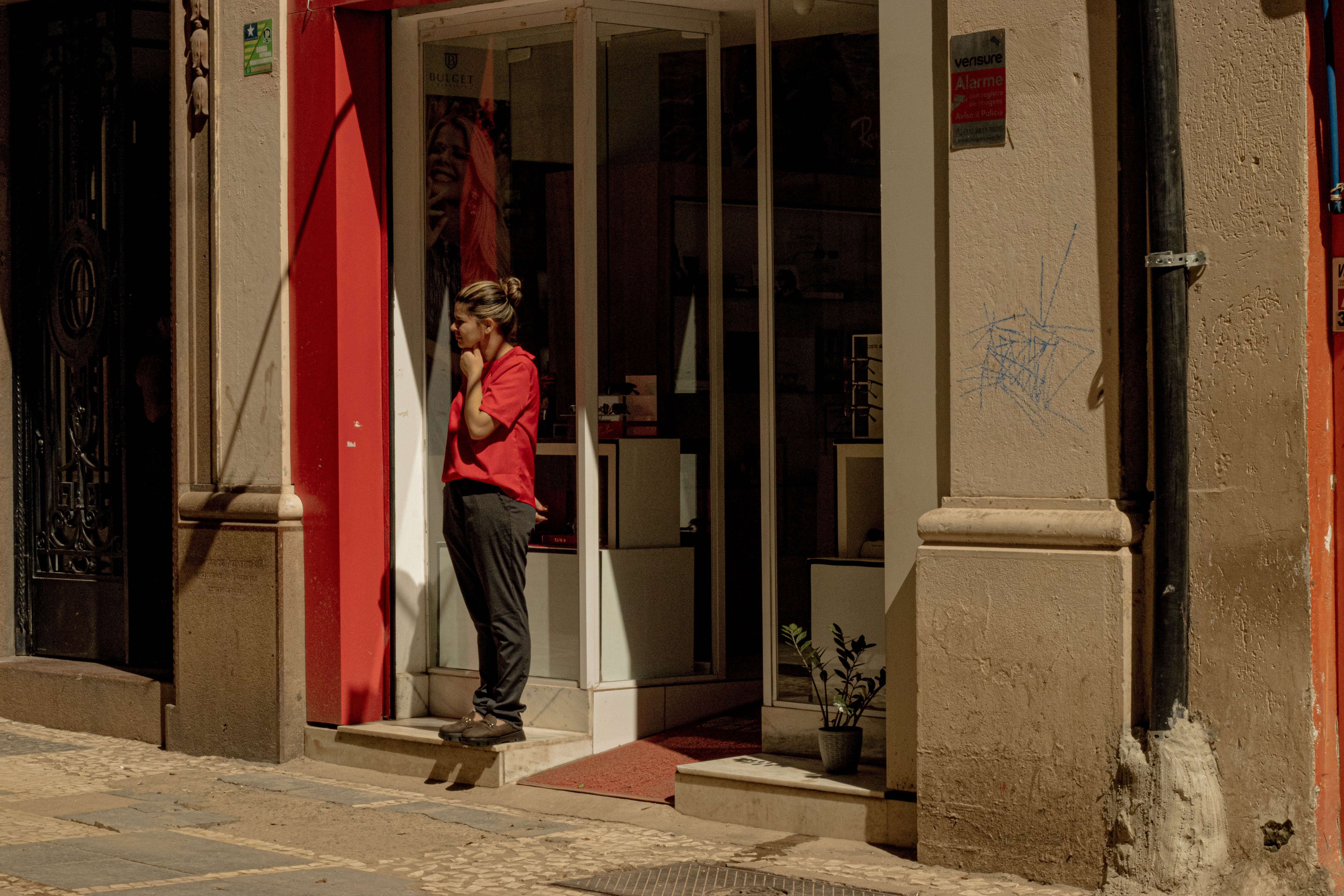 Two women smiling while arranging a vintage window display in a Lisbon street.