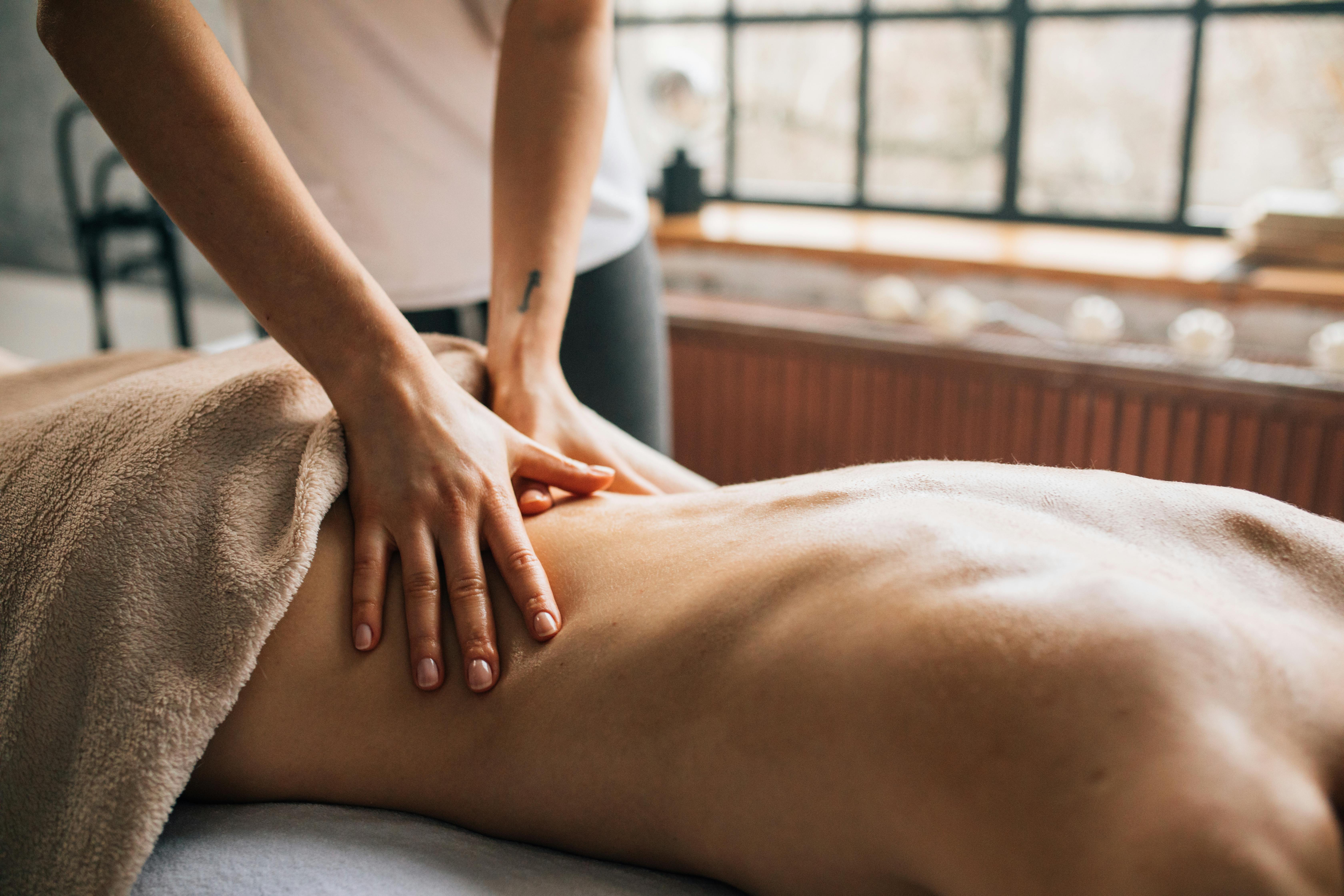 Relaxed person lying on a massage bed in a dimly lit room