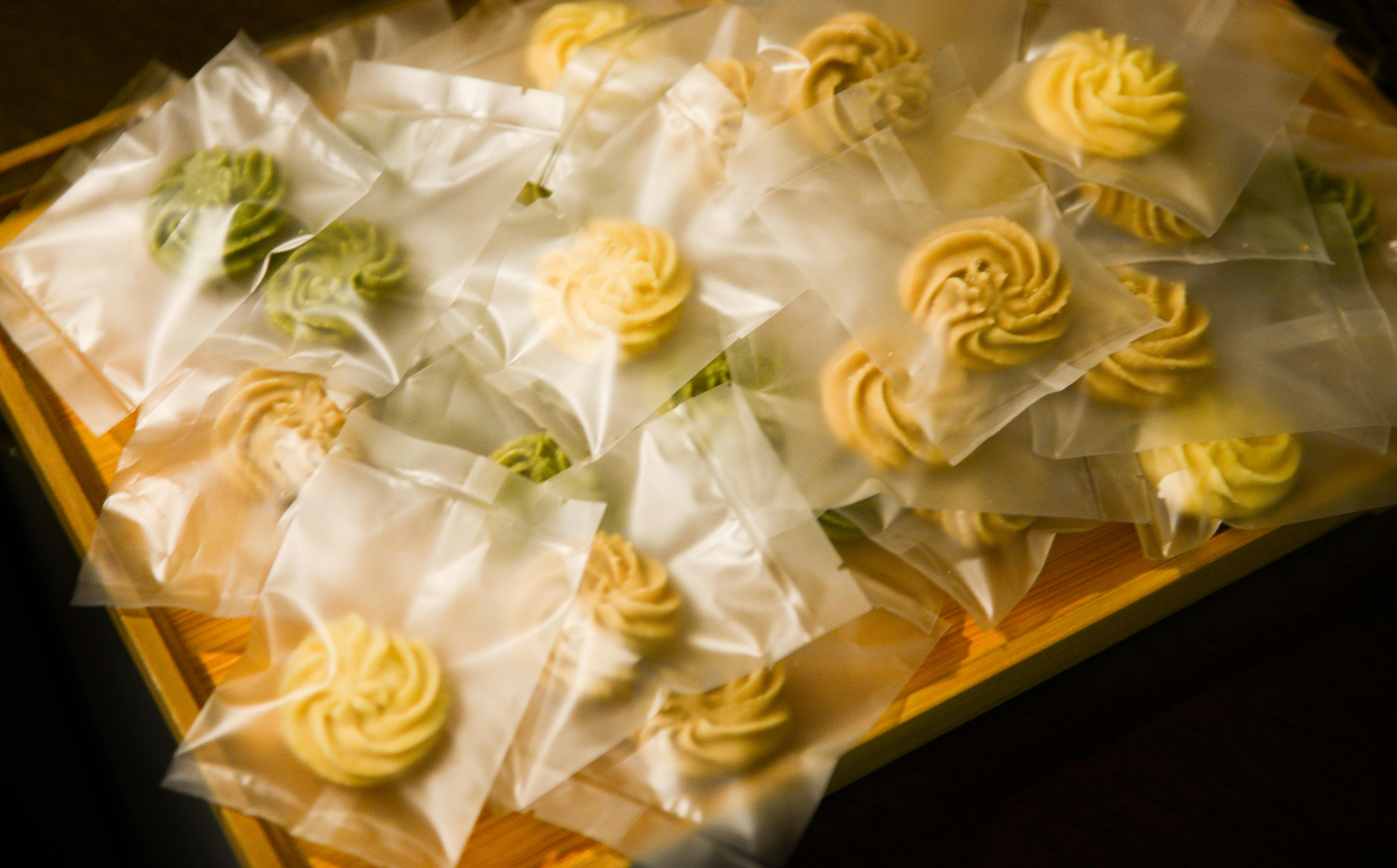A variety of dog-friendly treats and gourmet cookies arranged on a wooden serving tray.